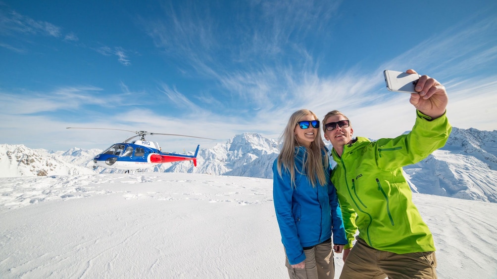 People taking pictures on snowpack with Mount Cook in background