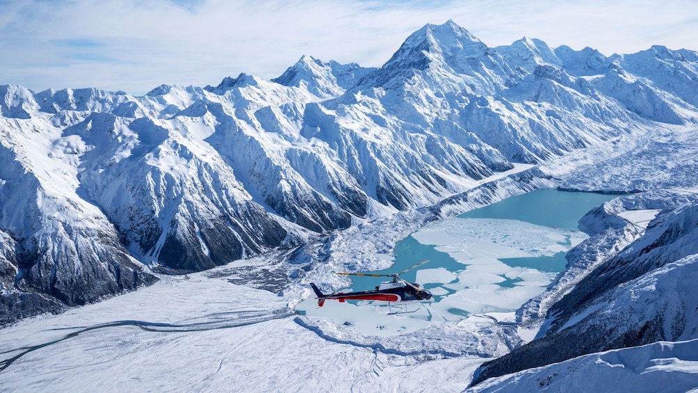 Helicopter hovers over glacier at base of Mount Cook in New Zealand