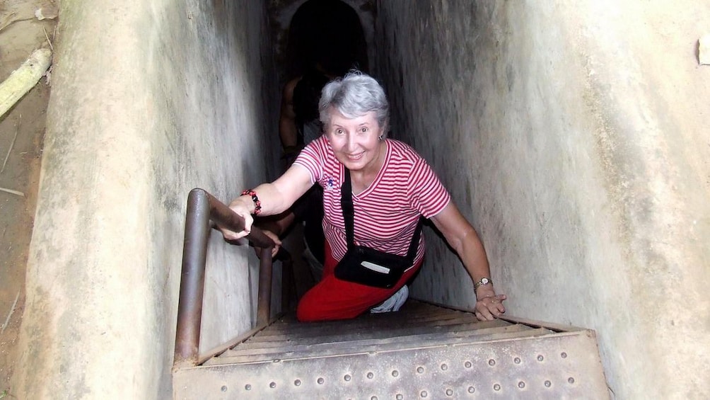 Woman climbing out of the Cu Chi Tunnel in Vietnam