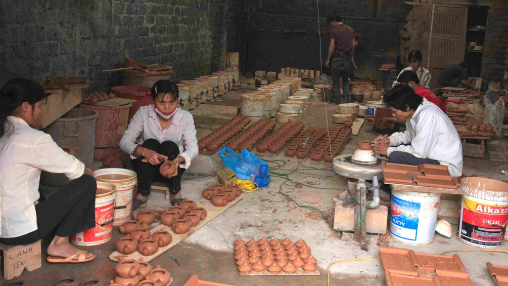 A vietnamese warehouse with people creating pottery