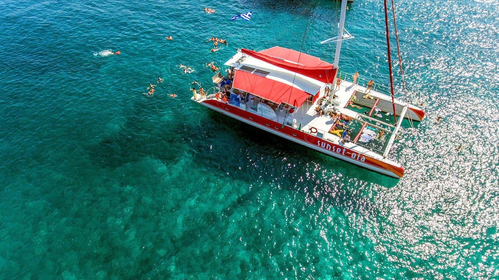 Aerial view people swimming around the catamaran off of Santorini, Greece