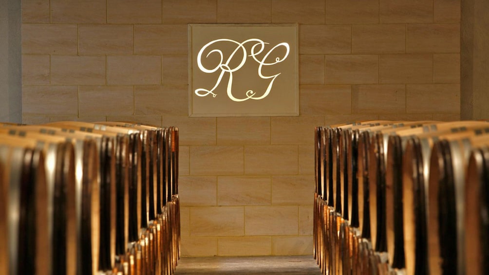 aisle lined with barrels looking toward winery logo on wall
