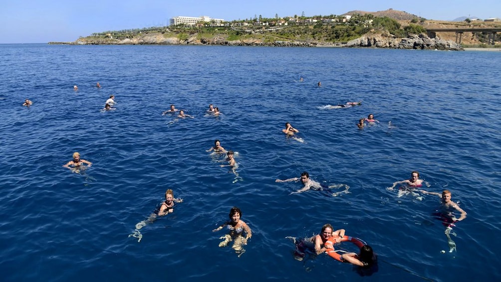 A group of people swim outside the coastline of Greece