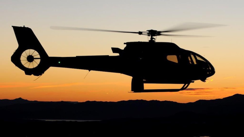 A silhouetted helicopter at sunset