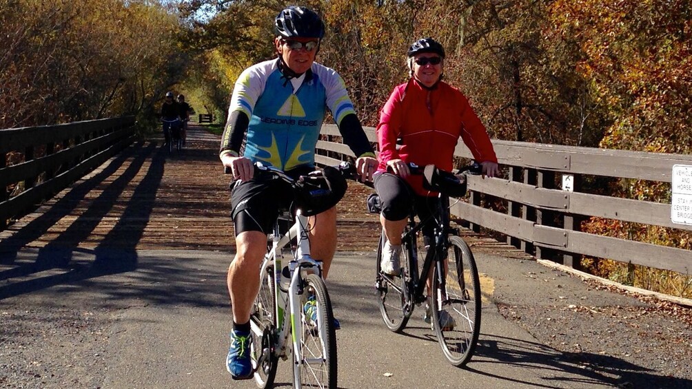 Couple on bikes ride through fall foliage 