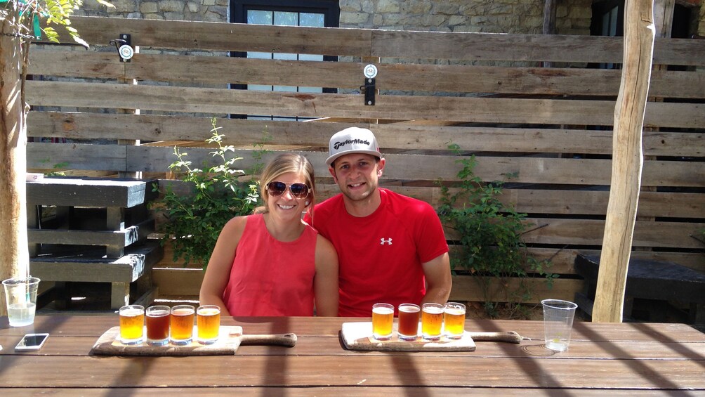 Couple looking at camera with beer samples in front of them