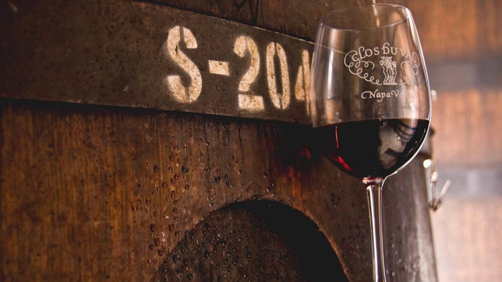 Close up of wine  glass against barrel of wine.