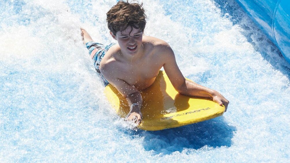 Foto 1 van 5. Young man sliding down water slide on board.