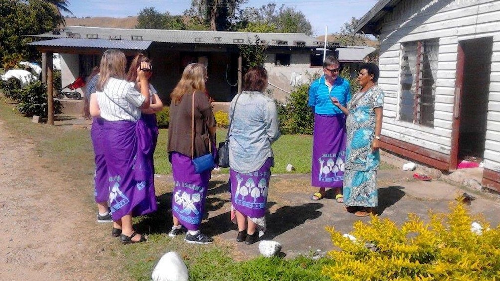 Guide with tour group wearing traditional skirts in Fiji