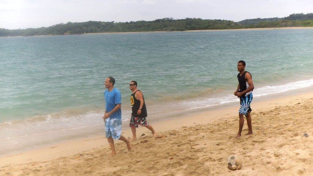 Three guys walking along the waters edge at the beach in Fiji