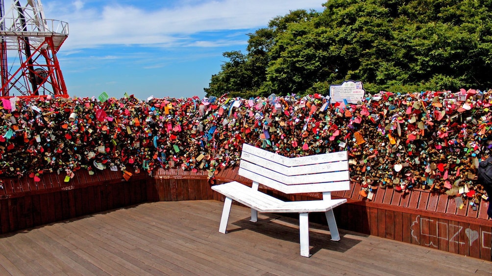 a wall of colorful crafted items near a white bench in Korea