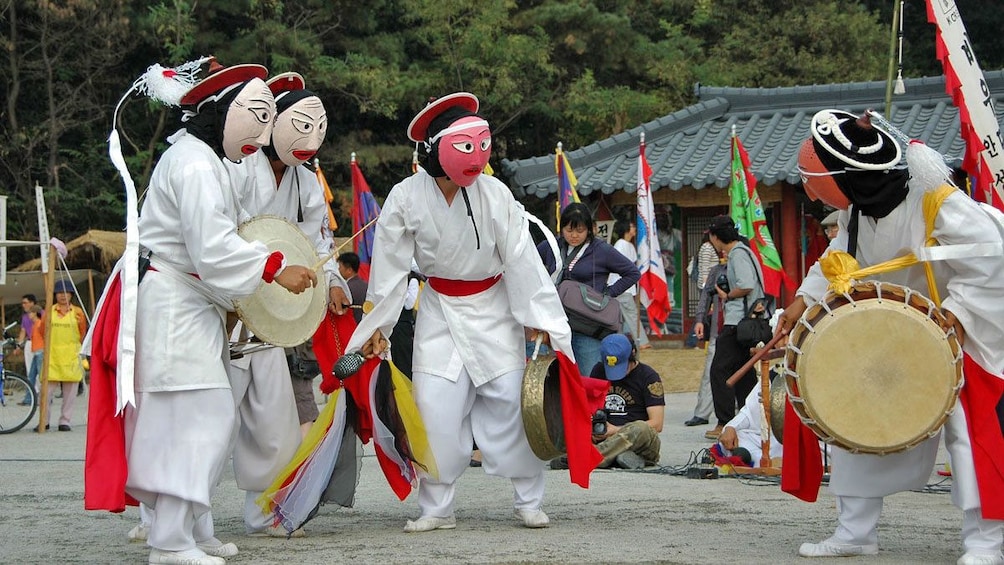 people in masks with drums