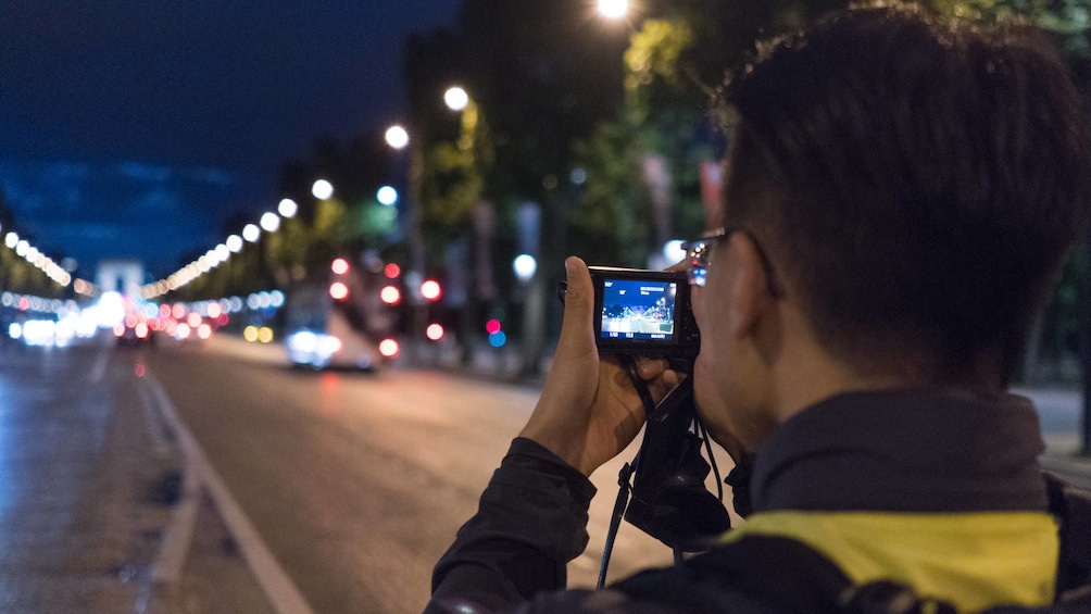 Photo of a person taking a photo at night in Paris