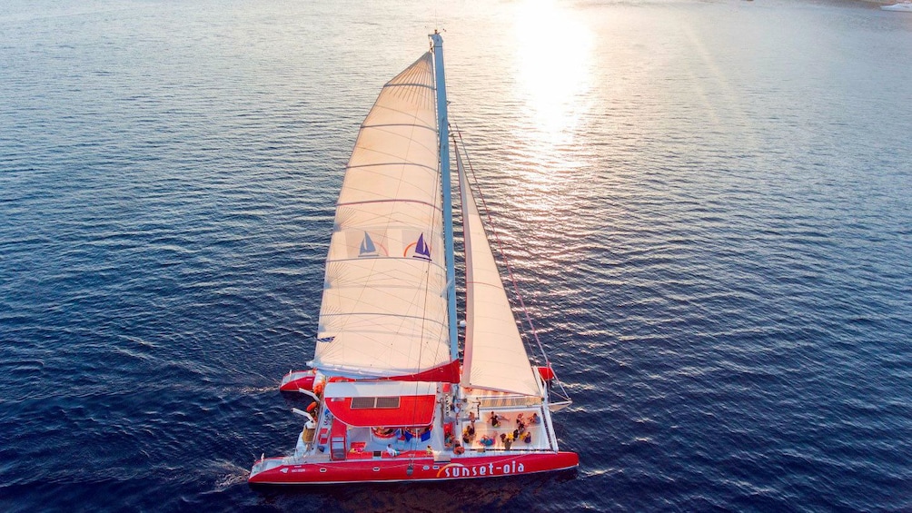 Aerial view of catamaran sailing as the sun sets in Santorini