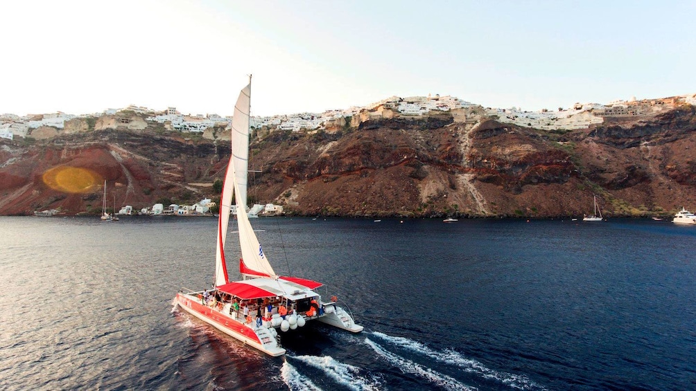Catamaran sailing near cliffs in Santorini