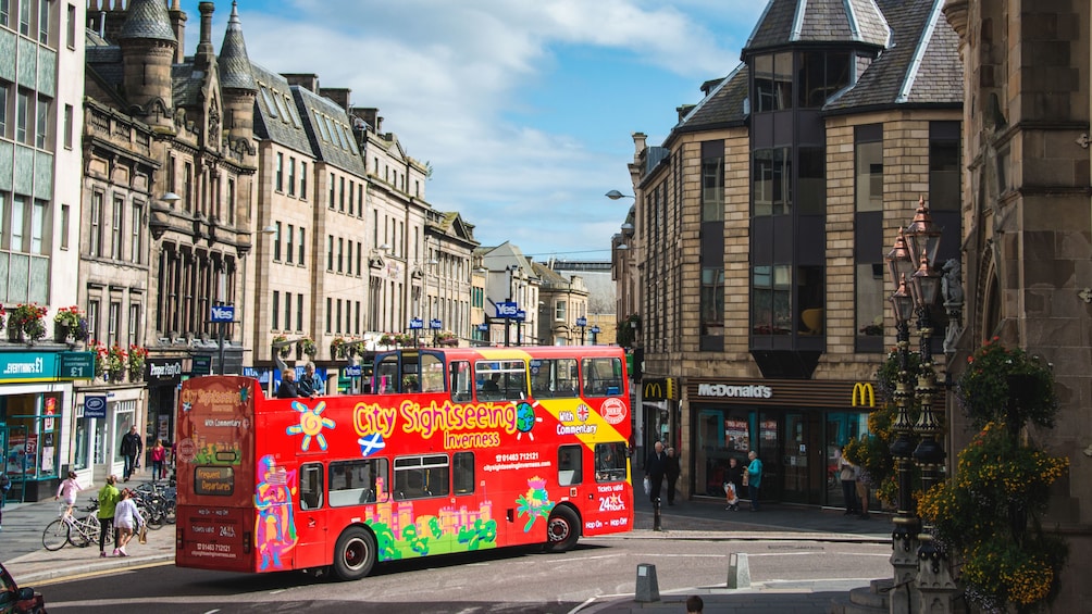 Red tour bus with several passengers aboard in Inverness.