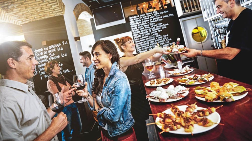 People socializing in bar with tapas and wine.