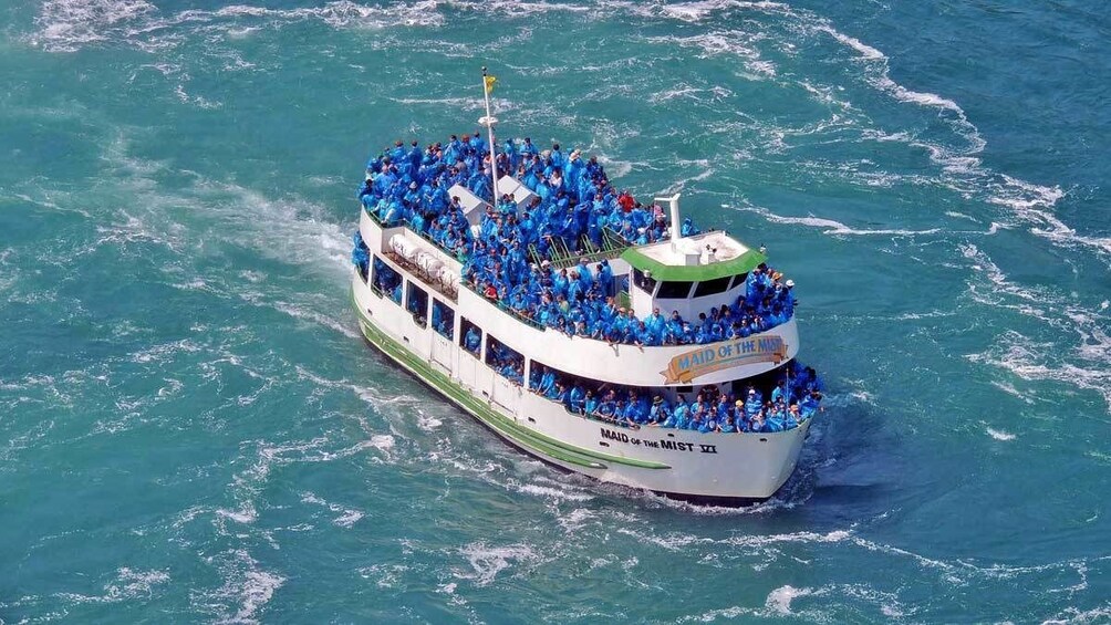 boat passengers in blue ponchos nearing the waterfall in Niagara Falls