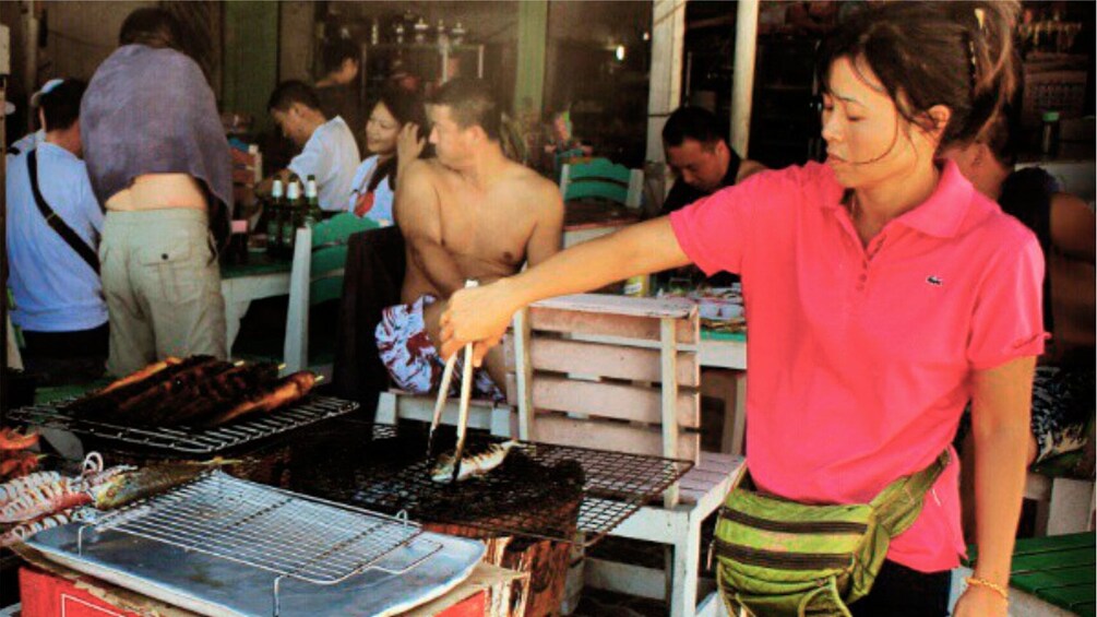 Show item 3 of 5. Woman grilling fish at a restaurant on Coral Island