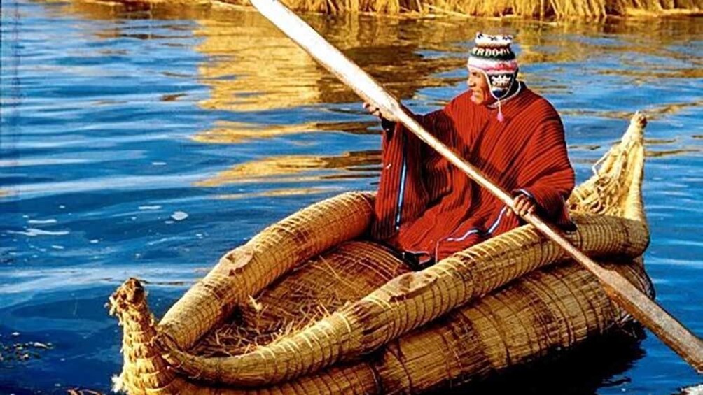 indigenous man paddling a straw woven canoe in Lima
