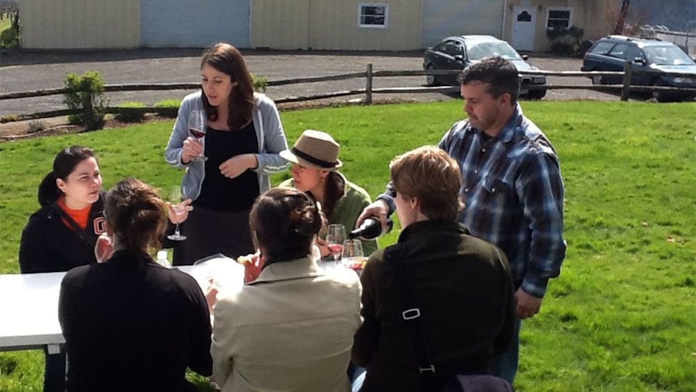 Sommelier pouring wine for a group outside at a winery in Portland