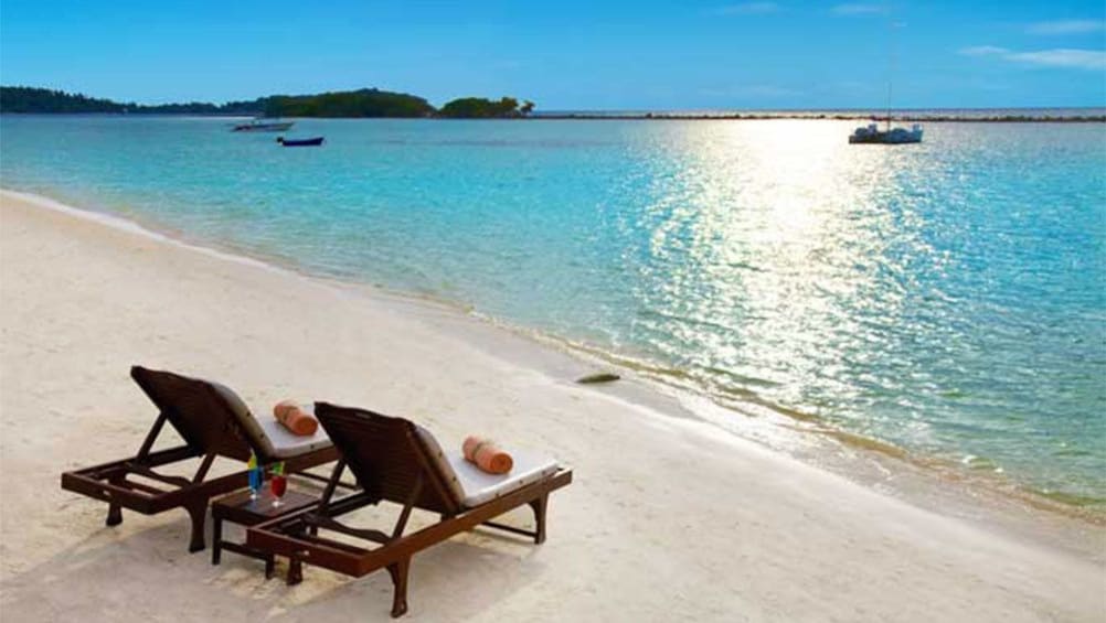 Pair of chaise lounges by the waters edge on the beach in Koh Samui