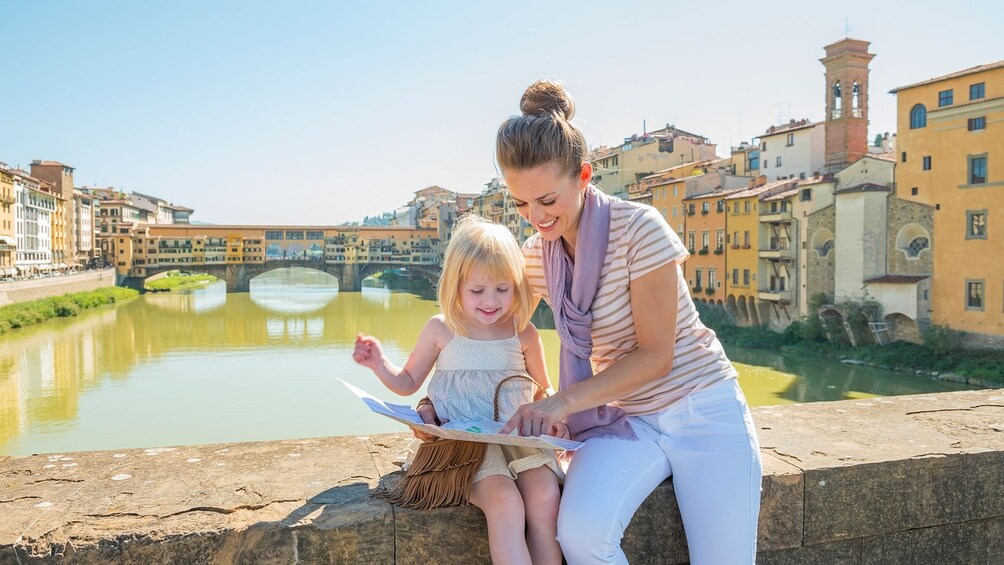 Mother and daughter reading map with river behind them.