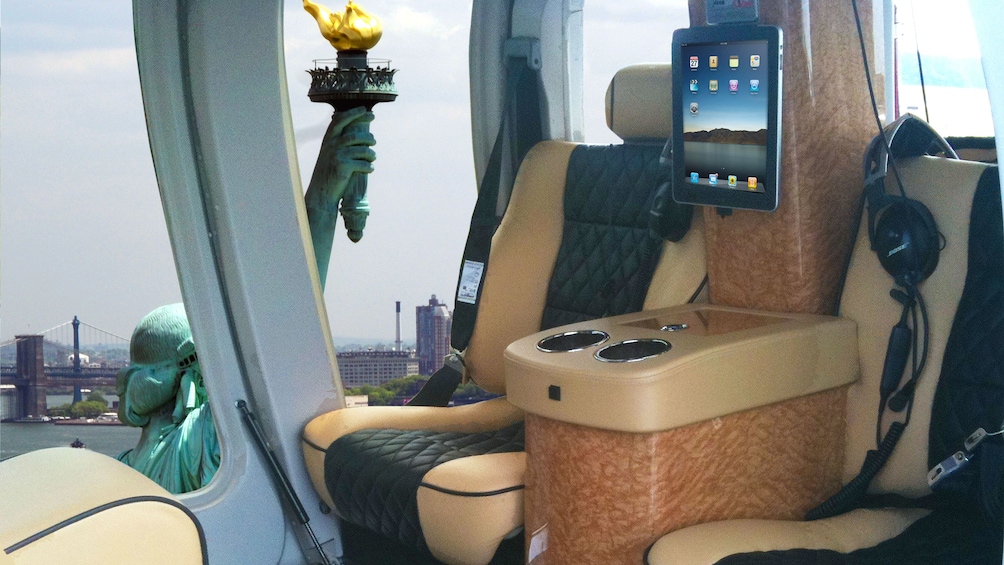 Interior view of helicopter with Statue of Liberty seen by window.
