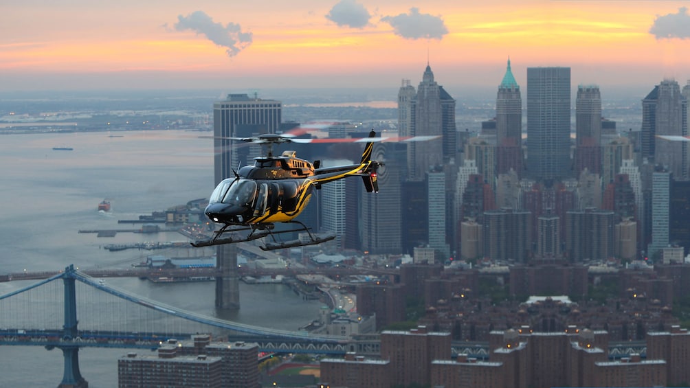 Helicopter flying over city at sunset.