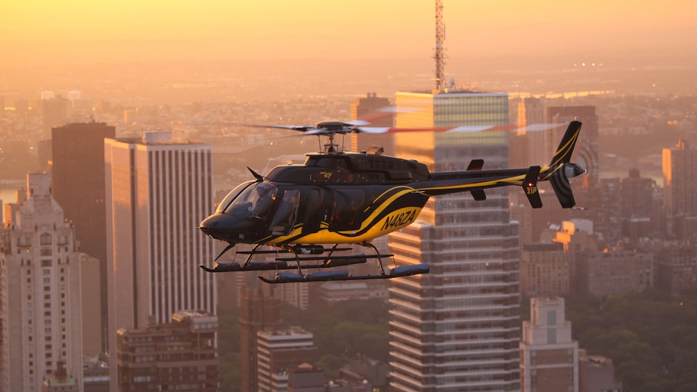 Helicopter flying over city at sunset.
