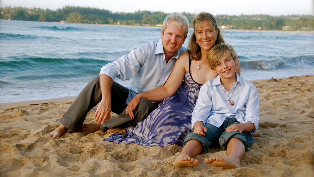 Family sitting on beach together in Kauai