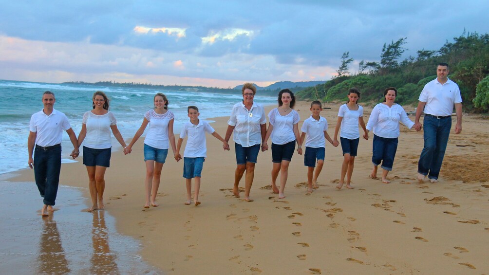 Family in white shirts and jeans in a row on the beach in Kauai