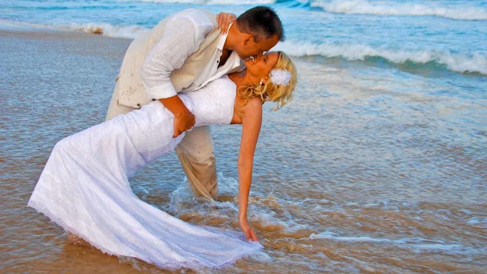 Man kissing woman in dipped pose on the beach
