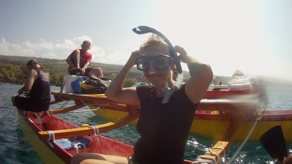People putting on snorkeling gear on an outrigger canoe in Hawaii