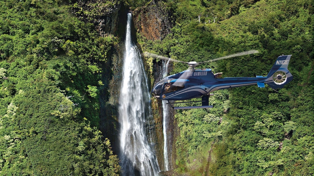 helicopter flying over waterfall in Kauai