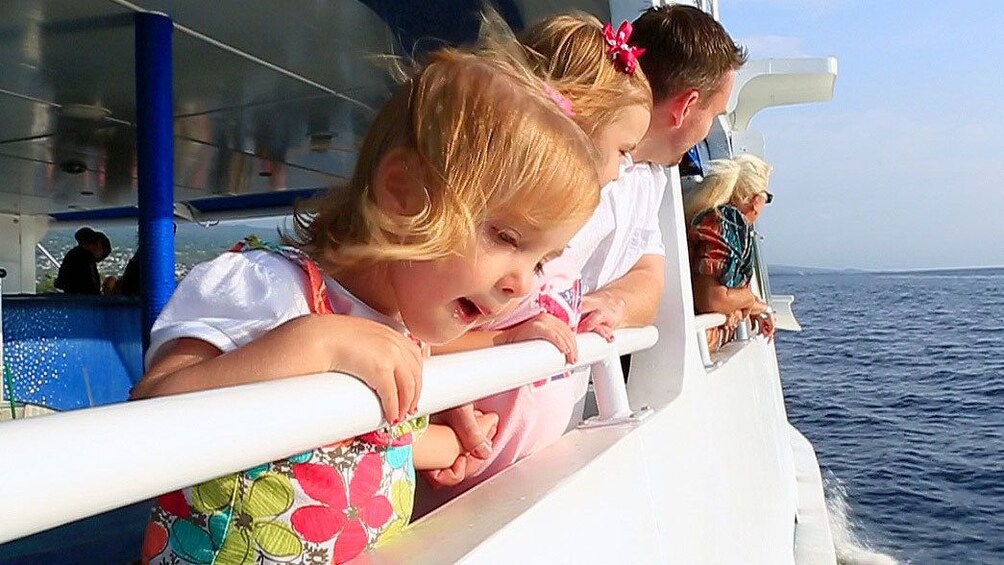 Two small girls on a cruise ship watching the whales in the pacific ocean