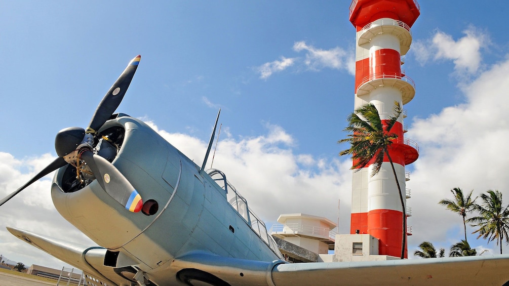 World war II naval fighter plane in front of control tower at the Pacific Aviation Musuem