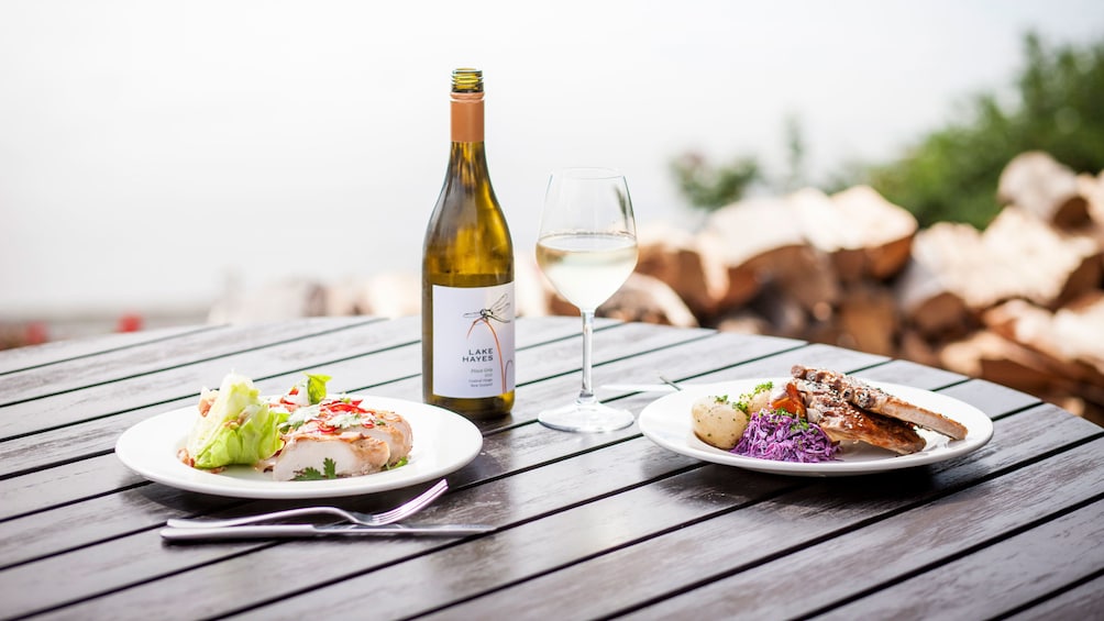 Outdoor patio table with wine, two plates of food