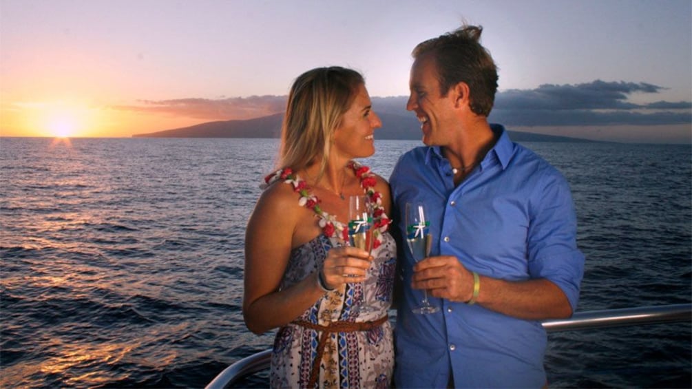 Couple toasting champagne on sailboat at sunset in Maui