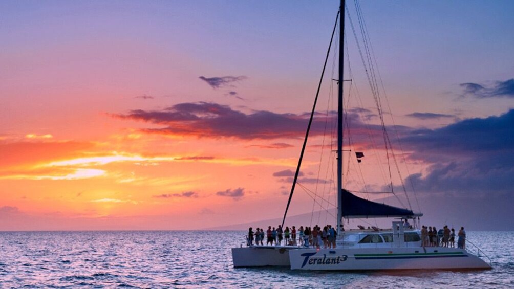 Catamaran with patrons afloat at sunset