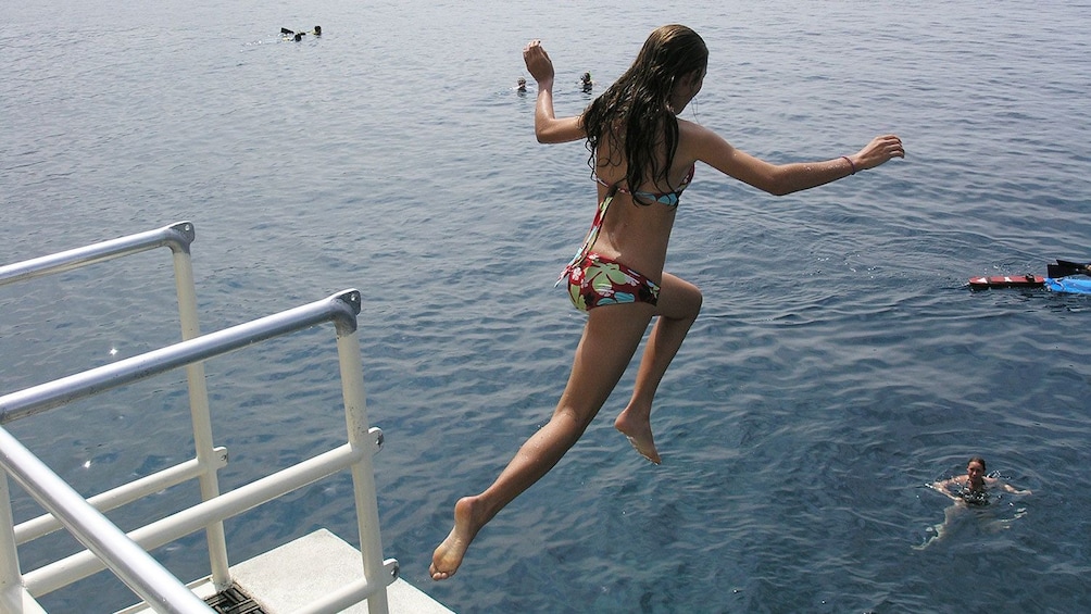 Young woman jumping into Pacific Ocean for a swim near the Big Island of Hawaii