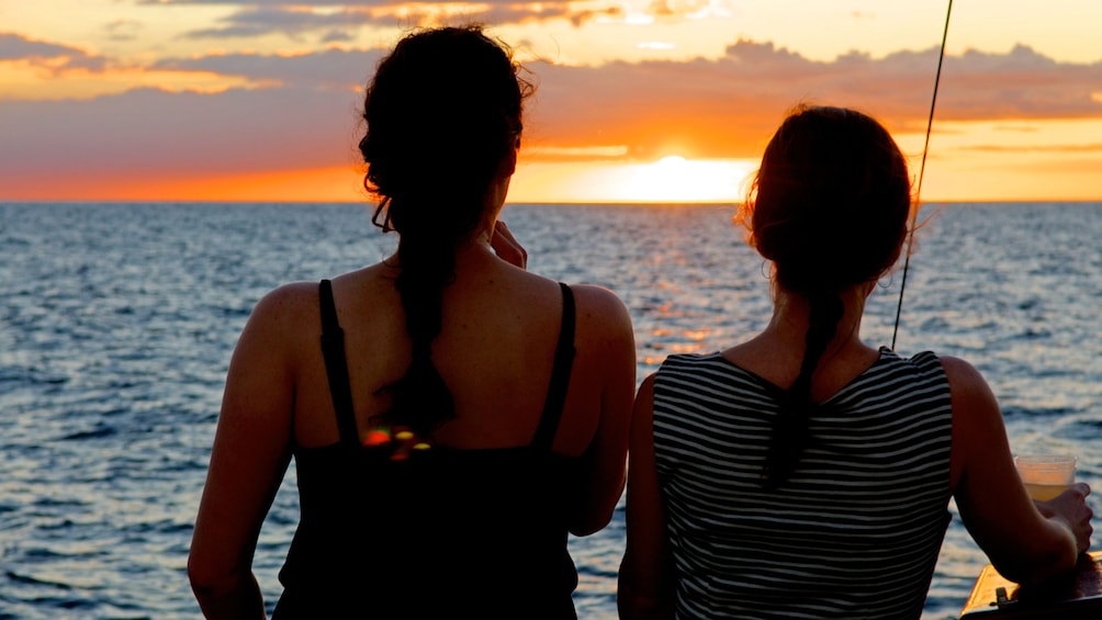 Two women watching the sunset on boat at Big Island