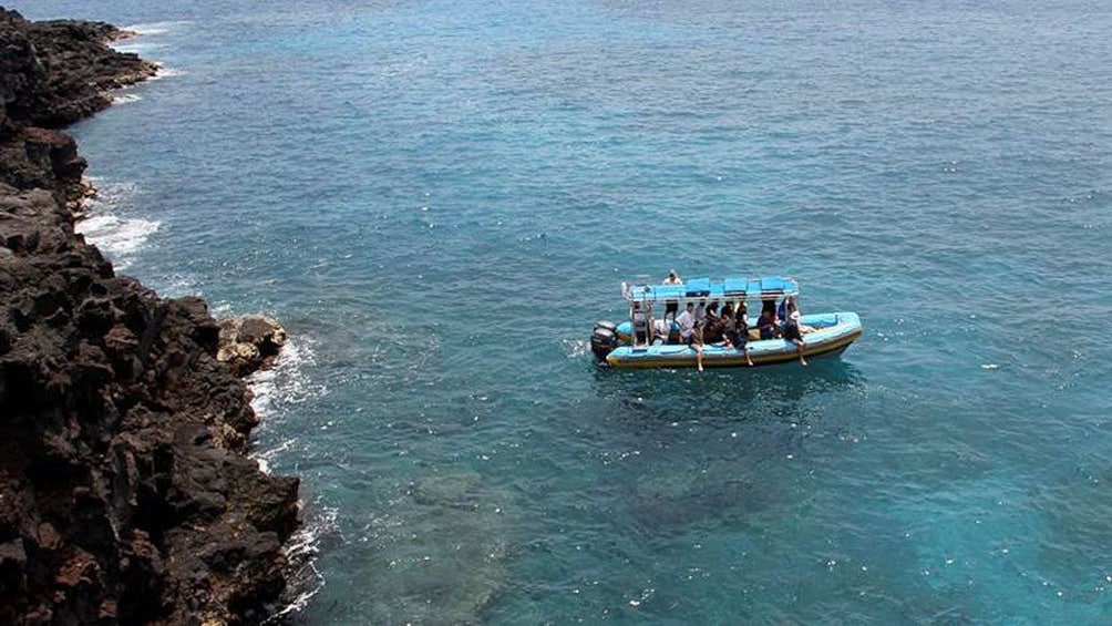 aerial on people on a boat near the cliff shore line in hawaii