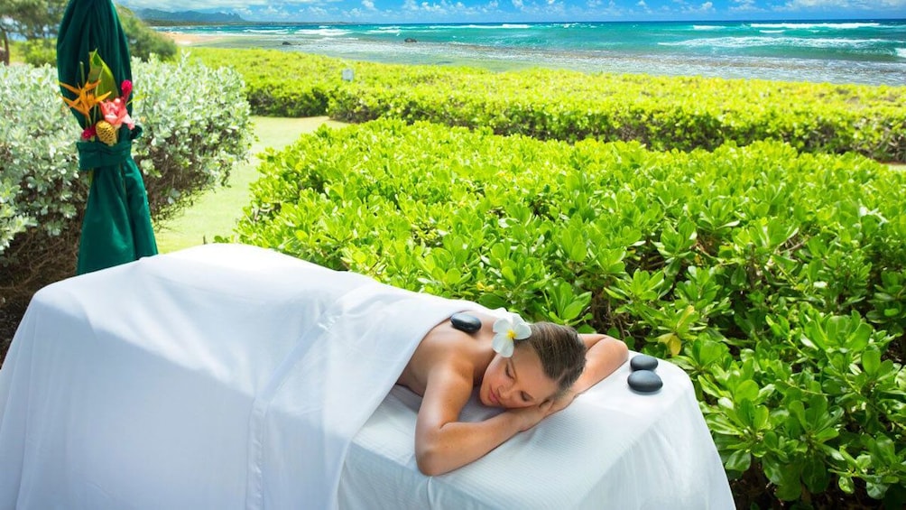 woman enjoying a hot stone massage at the beach in Kauai