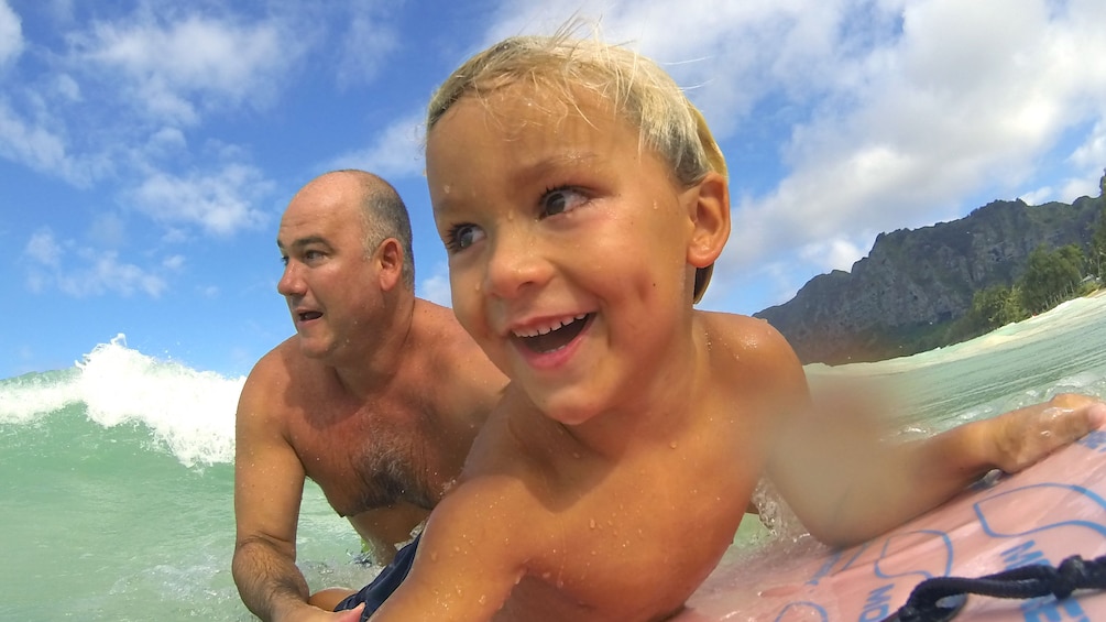 Boy and father on surf board in Kauai