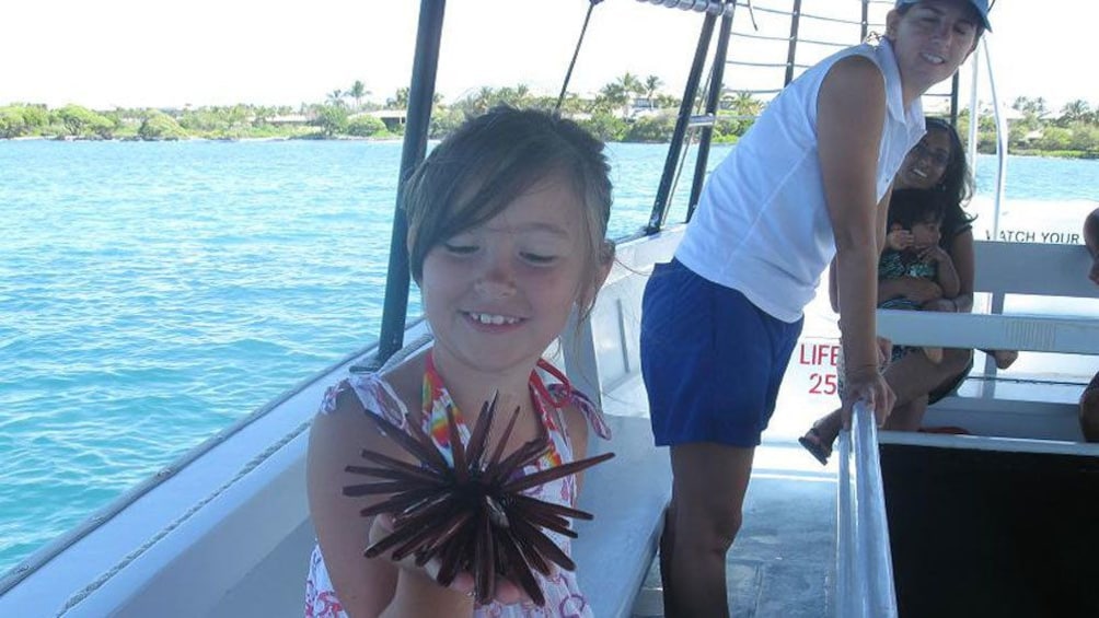 Young girl holding a sea urchin on the glass bottom boat in the Pacific Ocean near the Big Island of Hawaii 