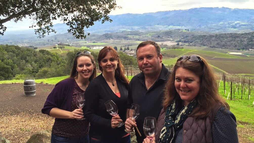 Group of guests posing in from of vineyard.