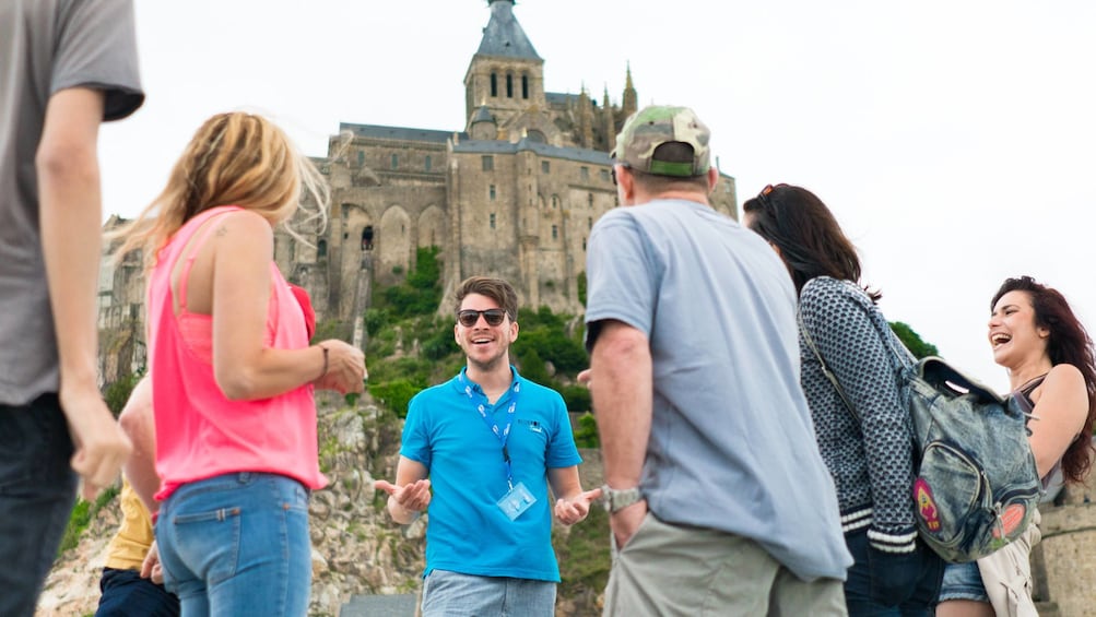 Guide laughs with tour goers at foot of Mont Saint-Michel