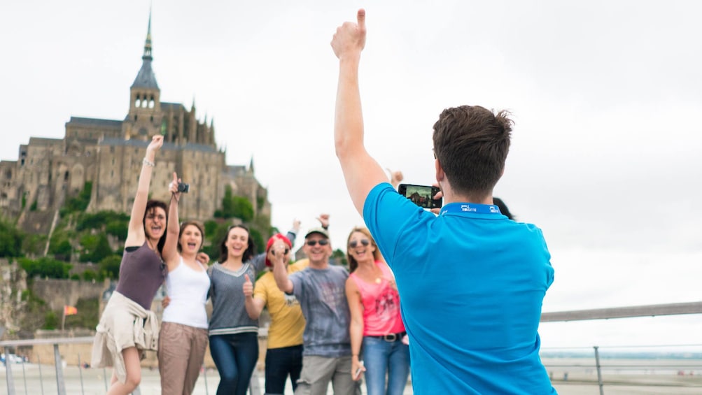 Tour guide takes photo of guests in front of Mont Saint-Michel