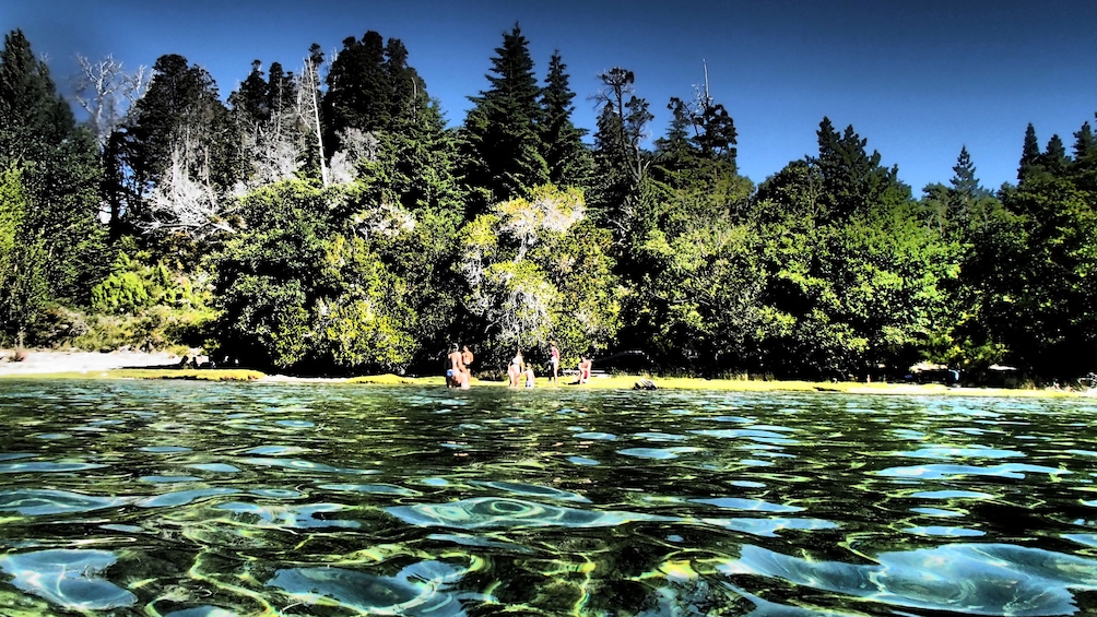 Crystal clear waters of San Carlos de Bariloche with swimmers on the shore